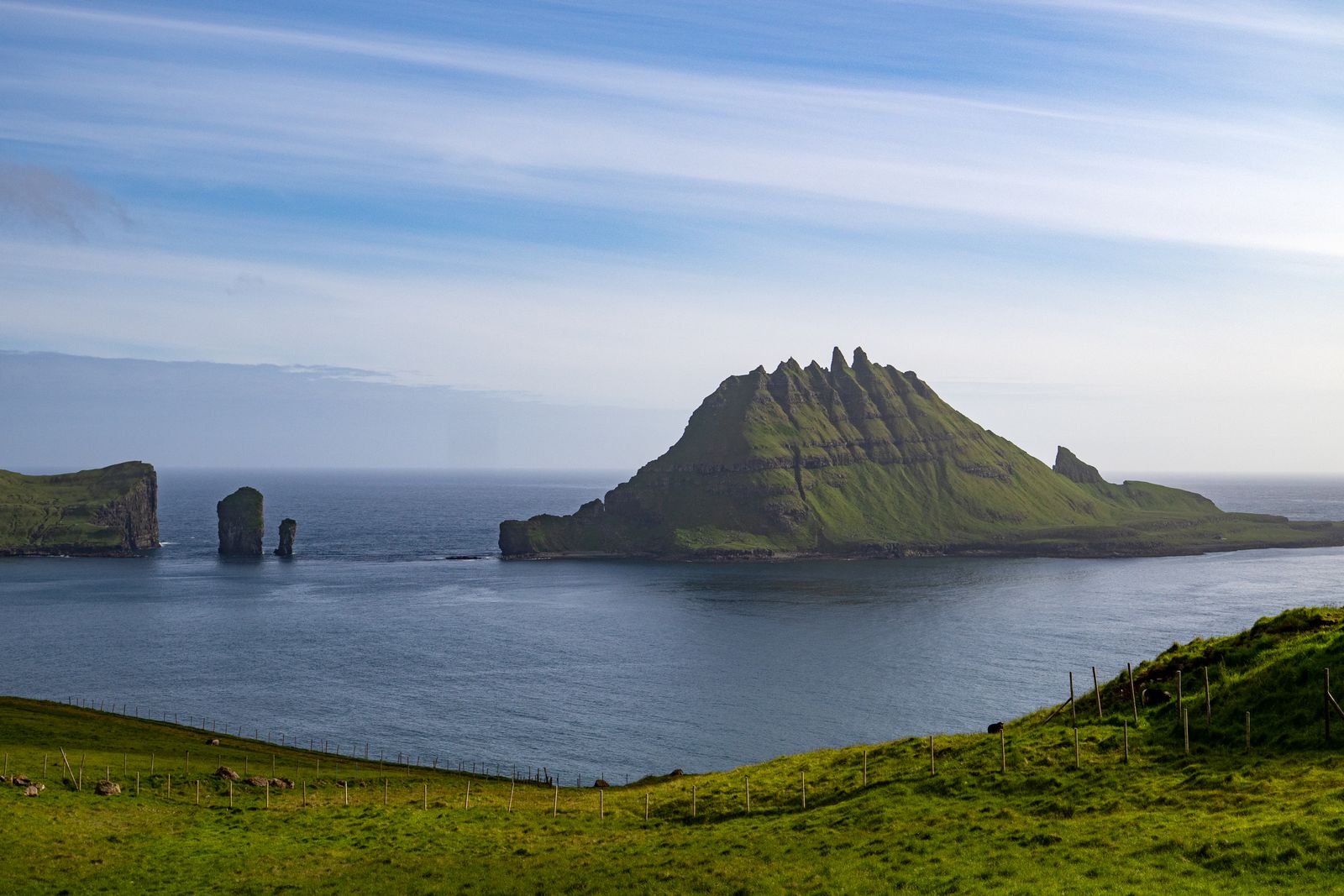 The sea stacks of Drangarnir and the jagged islet of Tindhólmur across calm water