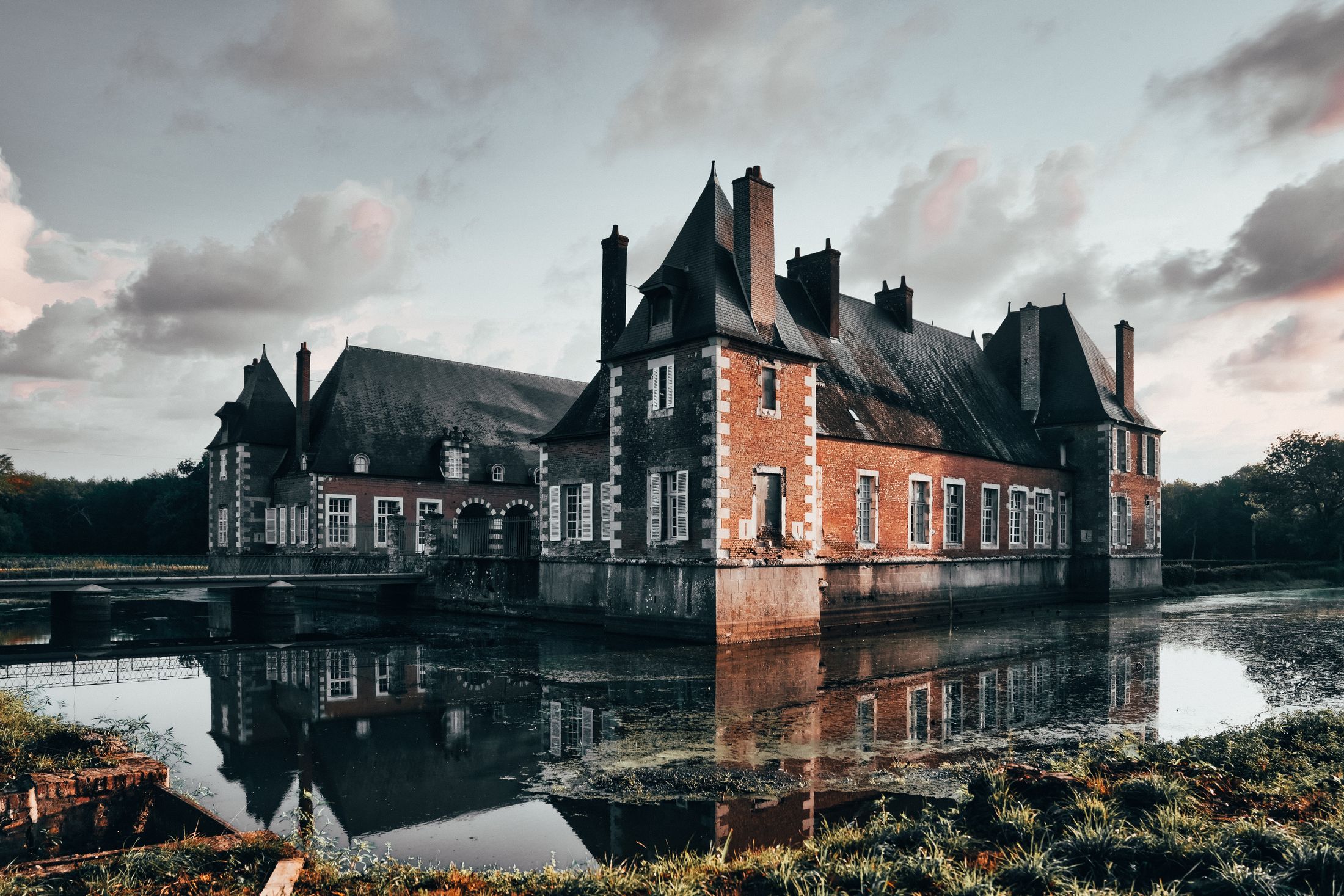 A moated French château mirrored in still water at twilight