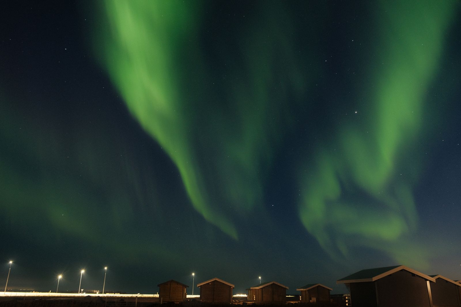 The northern lights unfurling over lodge cabins at night