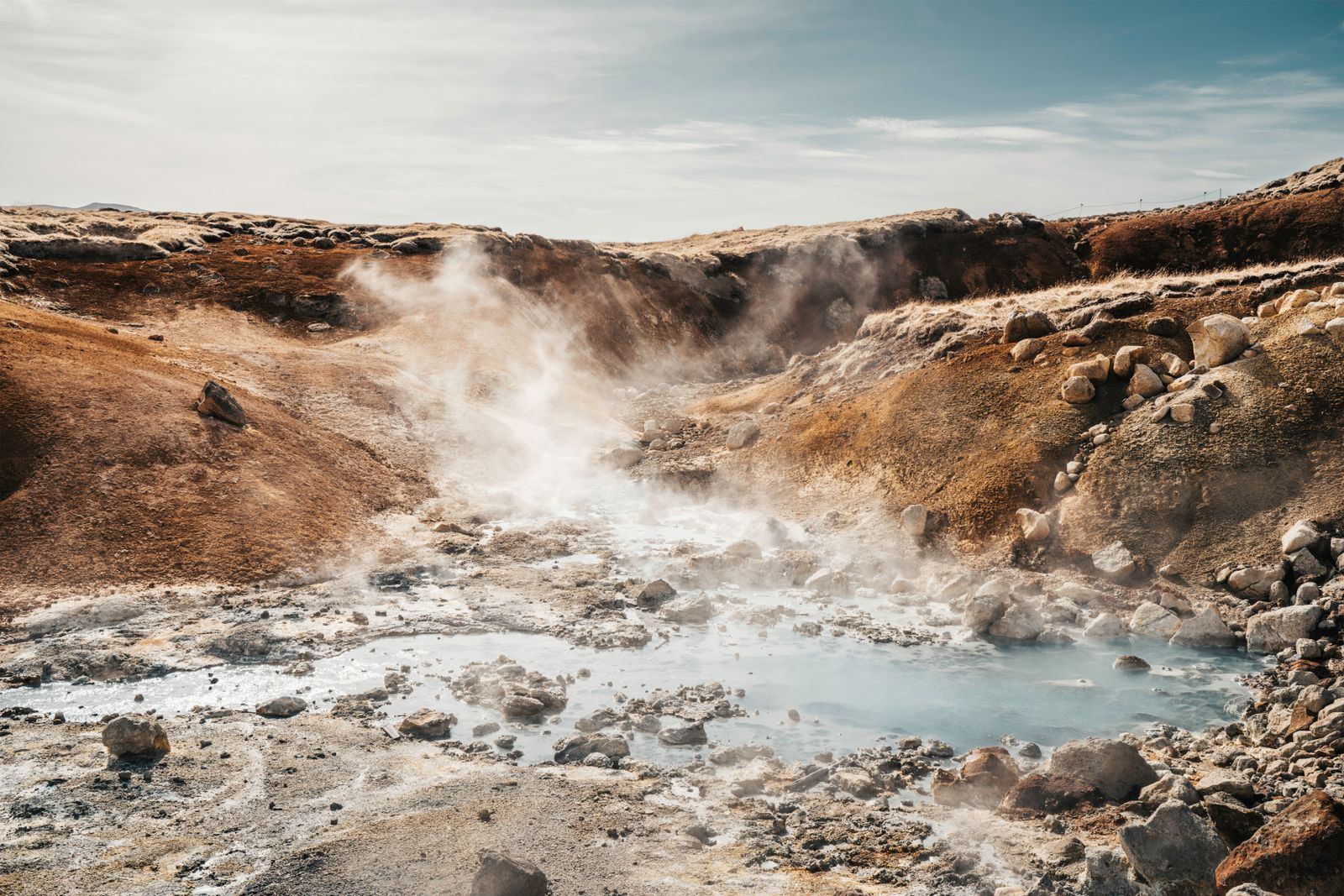 Steam rising from a geothermal spring in a volcanic landscape