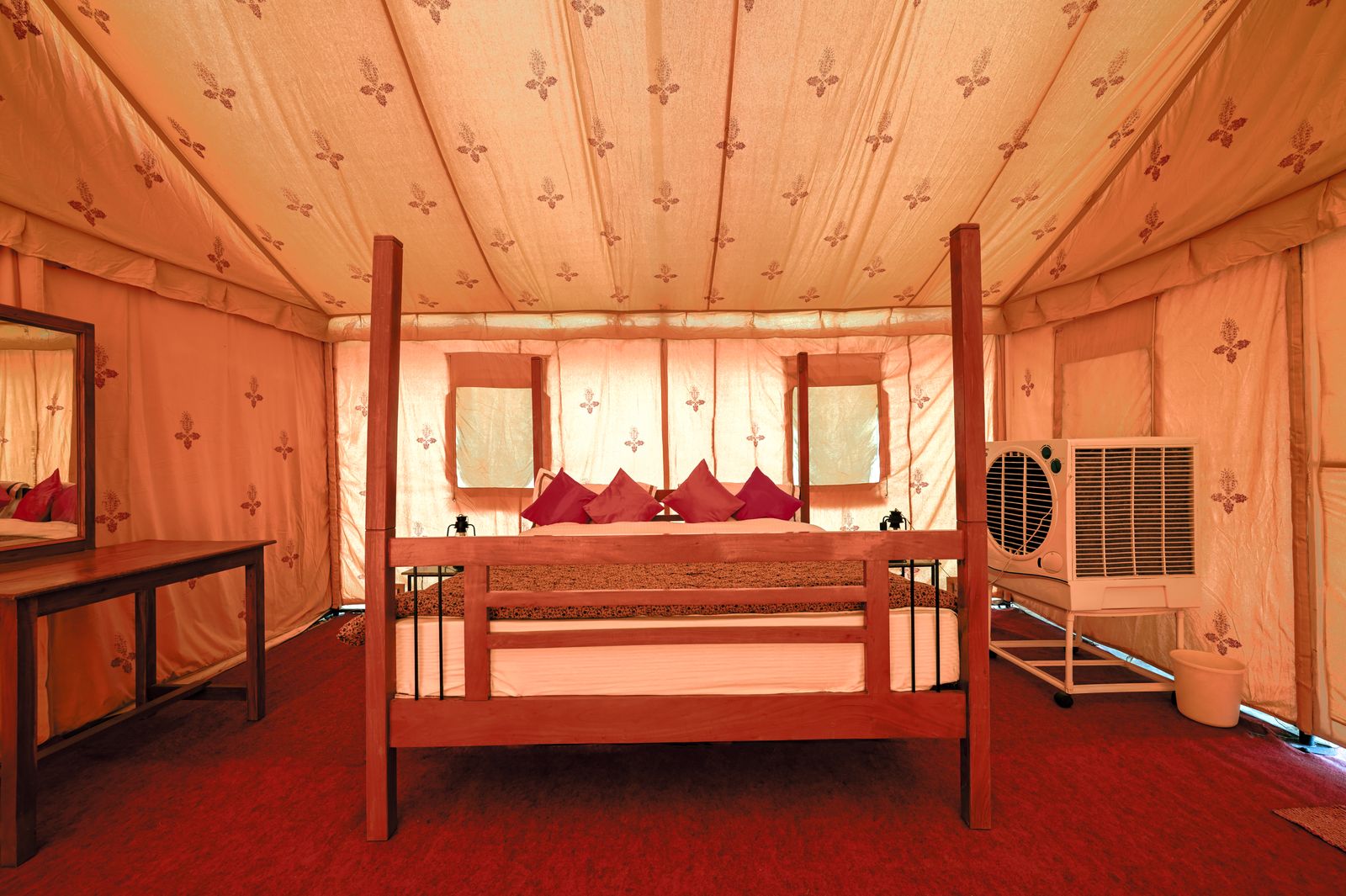 A lamplit bed inside a canvas safari tent