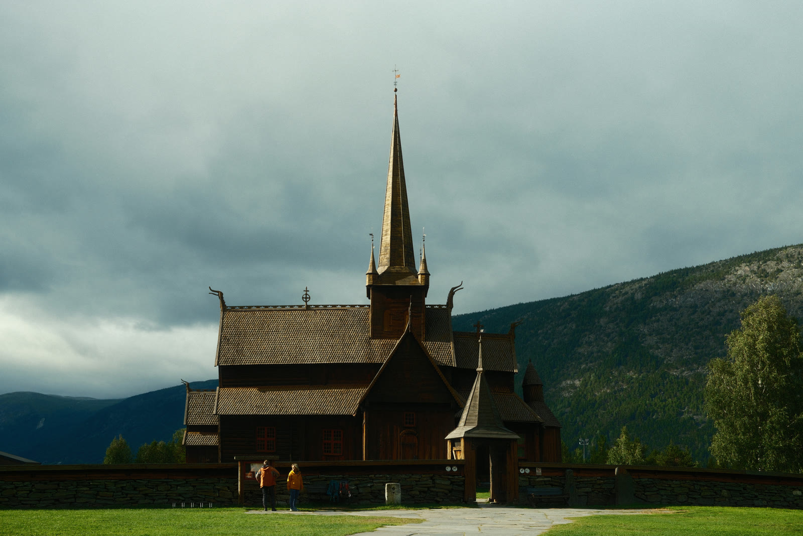 A dark wooden stave church with tiered roofs against the sky