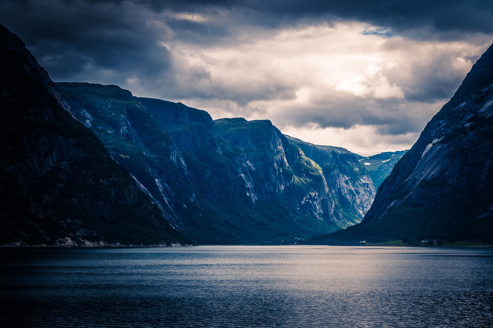 A Norwegian fjord at dusk, sheer mountains mirrored in still water