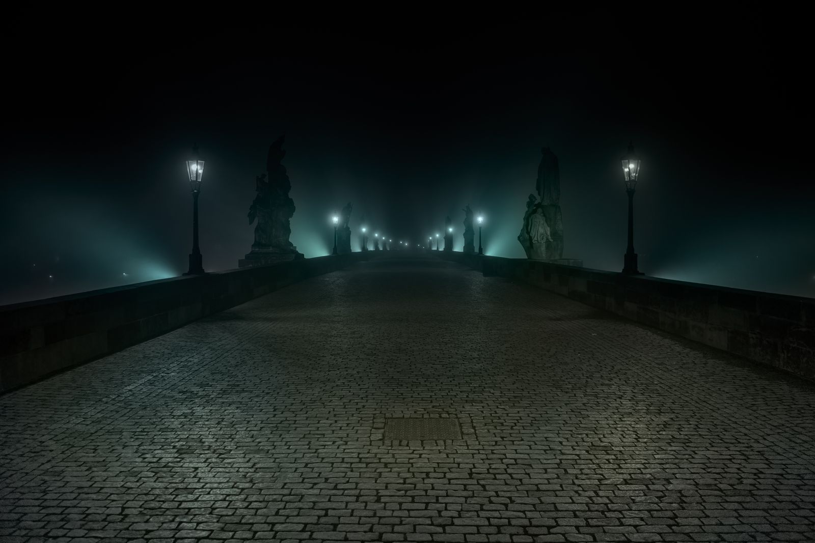 Charles Bridge under its lamps before dawn