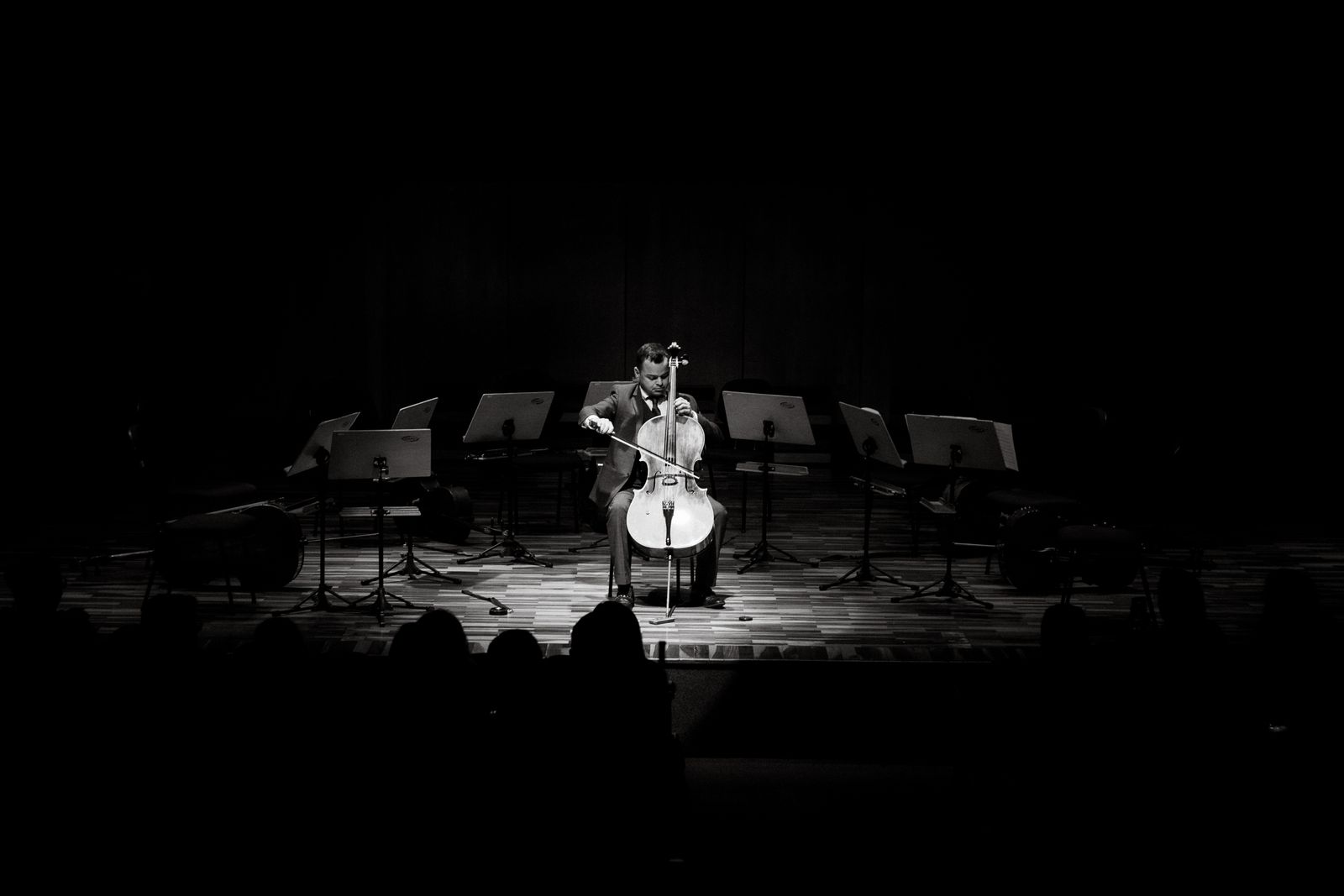 A cellist playing alone on a darkened stage