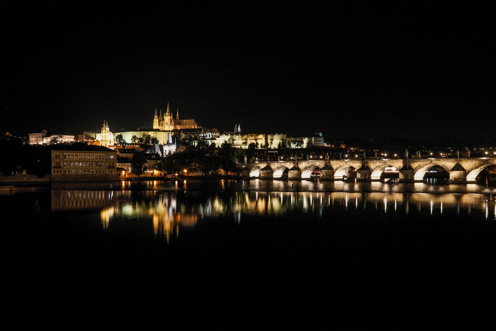 Prague's bridges and castle lit above the night river
